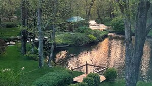 Un parque tranquilo con un estanque, un puente de madera y un pabellón.