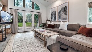 A spacious living room with a large window, a television, a sofa, and a coffee table.