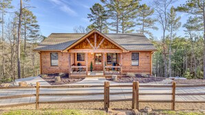 A log cabin with a front porch, a covered patio, and a fenced driveway. - Ellijay Escape: Hot Tub, Fireplace, Peaceful Views (Ellijay)