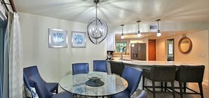 Un'elegante sala da pranzo moderna con tavolo in vetro, sedie blu e lampadario.
