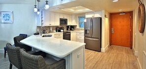 A modern kitchen with white cabinetry, stainless steel appliances, and a central island.