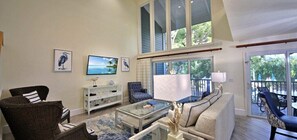 A spacious living room with a large window, a sofa, a coffee table, and a television.