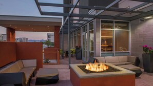 Un espacio al aire libre con fogones, asientos acolchados y vistas al interior a través de amplios ventanales.