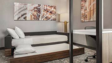 A hotel room with a bed, a desk, and two wall-mounted artworks.