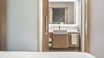 A modern bathroom with a wooden vanity, a mirror, and a white sink.