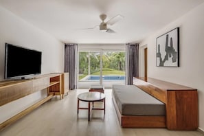 Una sala de estar moderna con un televisor de pantalla plana, muebles de madera, un ventilador de techo y vista a una piscina.
