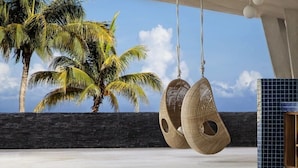 Una habitación con vistas a palmeras, un sillón colgante y un muro de azulejos.
