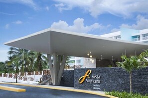 Ein moderner Hotel Eingang mit einer großen Markise, Palmen und einem Schild für Fiesta Americana.
