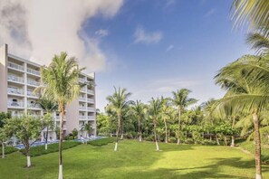 A hotel courtyard with a pool, palm trees, and a multi-story building.