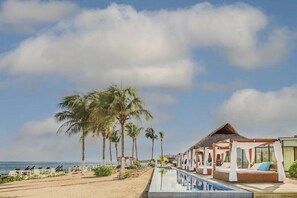 A resort with a pool, beach chairs, and palm trees. - Cozumel | Couples All-Inclusive Getaway | Pool + Beach (Cancun)