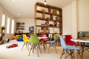 Un cuarto de juegos infantil con sillas coloridas, una estantería de madera y juguetes.