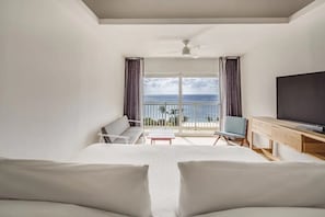 Ein Hotelzimmer mit Balkon, Fernseher, Sofa und Schreibtisch.