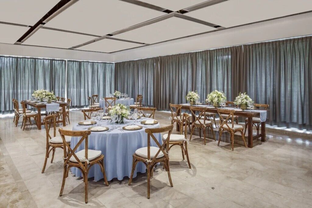 A banquet hall with round tables, white tablecloths, and floral centerpieces.
