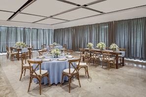Une salle de banquet avec des tables rondes, des nappes blanches et des centres de table floraux.