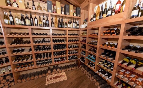 A wine cellar with wooden shelves and racks filled with wine bottles.