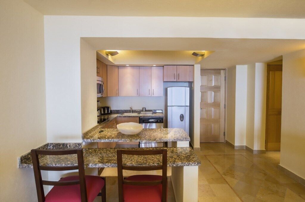 A kitchen with granite countertops, a white sink, and a stainless steel refrigerator.