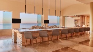 Un'area bar con un lungo bancone, diverse sedie e vista sull'oceano.