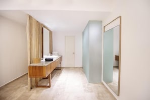 A modern bathroom with a wooden vanity, a large mirror, and a frosted glass partition.