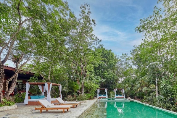 A pool area with lounge chairs and a canopy structure.