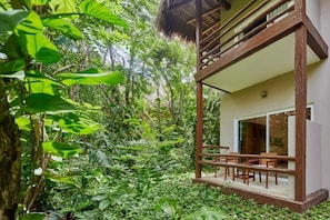A modern house with a glass balcony overlooking a lush garden.