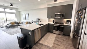 A modern kitchen with grey cabinets, stainless steel appliances, and a large island. - The Heights Cozy Stay - Gym&pool 12mins to Midtown and Downtown (Houston)