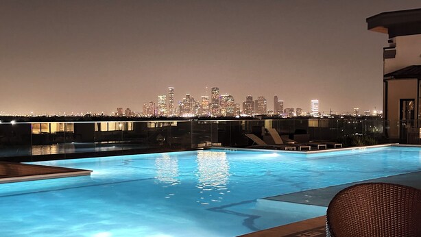 A rooftop pool with a city skyline view at night. - The Heights Cozy Stay - Gym&pool 12mins to Midtown and Downtown (Houston)
