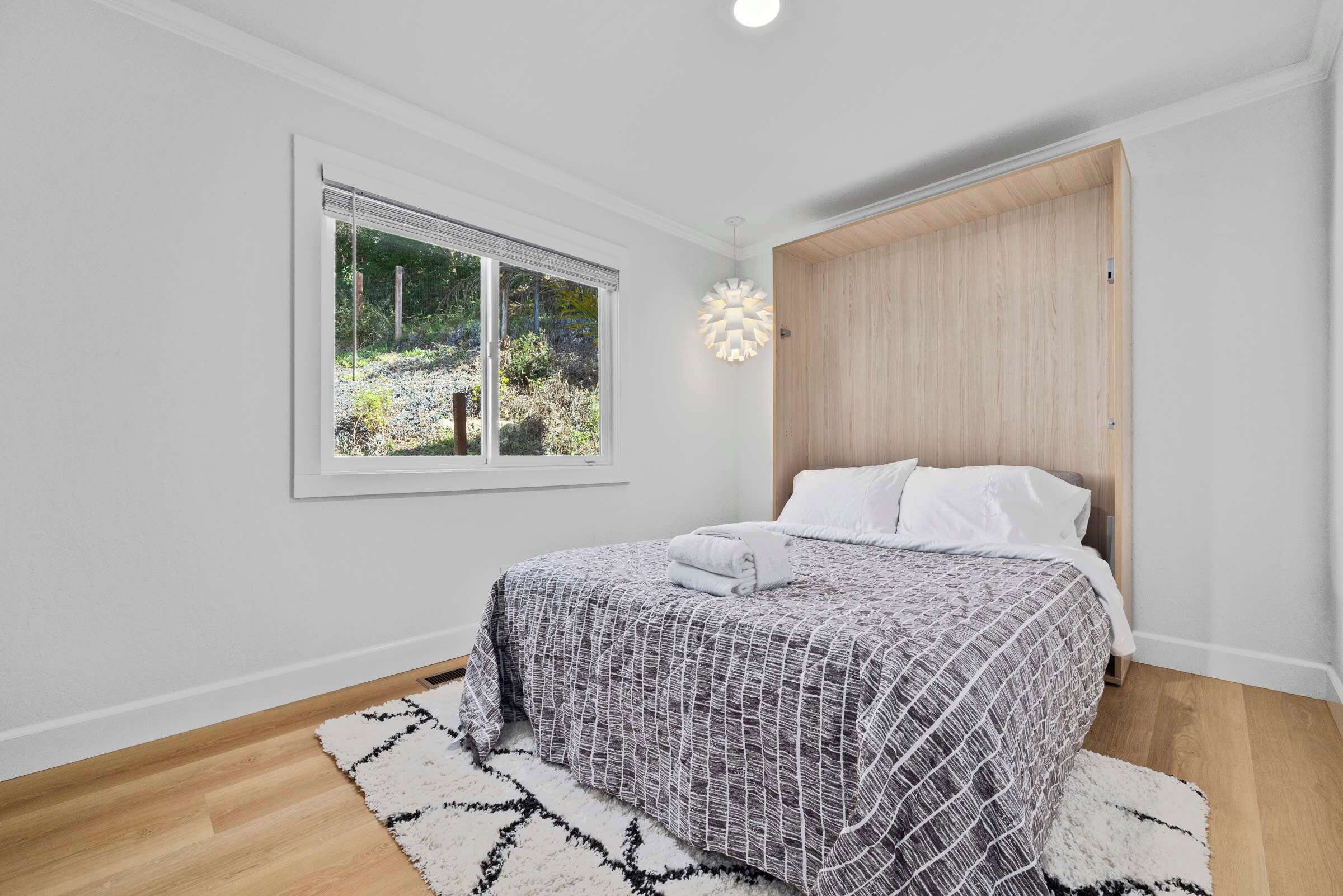 Un dormitorio con cama, ventana, puerta y lámpara.
