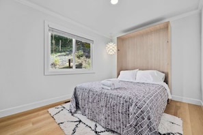A bedroom with a bed, a window, a door, and a light fixture. - Serene Mountain Home with Ocean View! (Aptos)