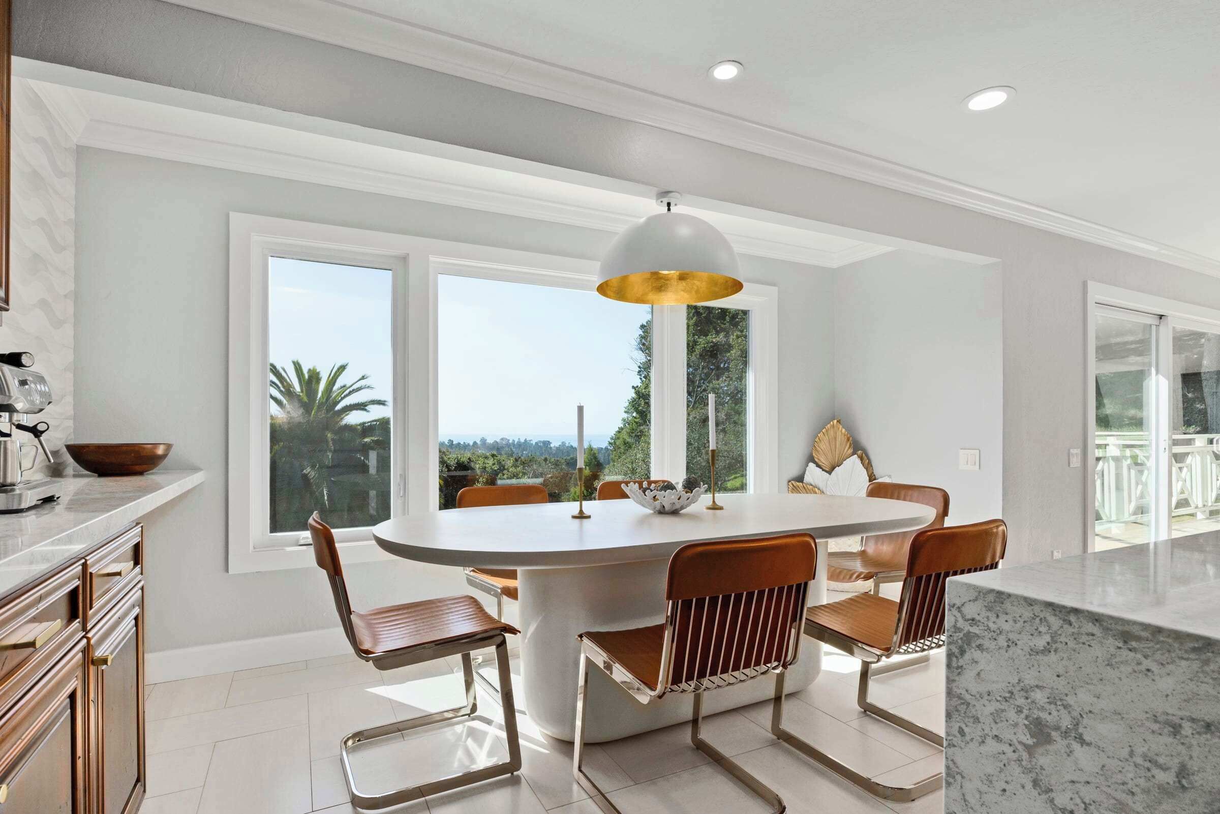 A modern kitchen with a round dining table, white cabinetry, and a view of the outdoors.