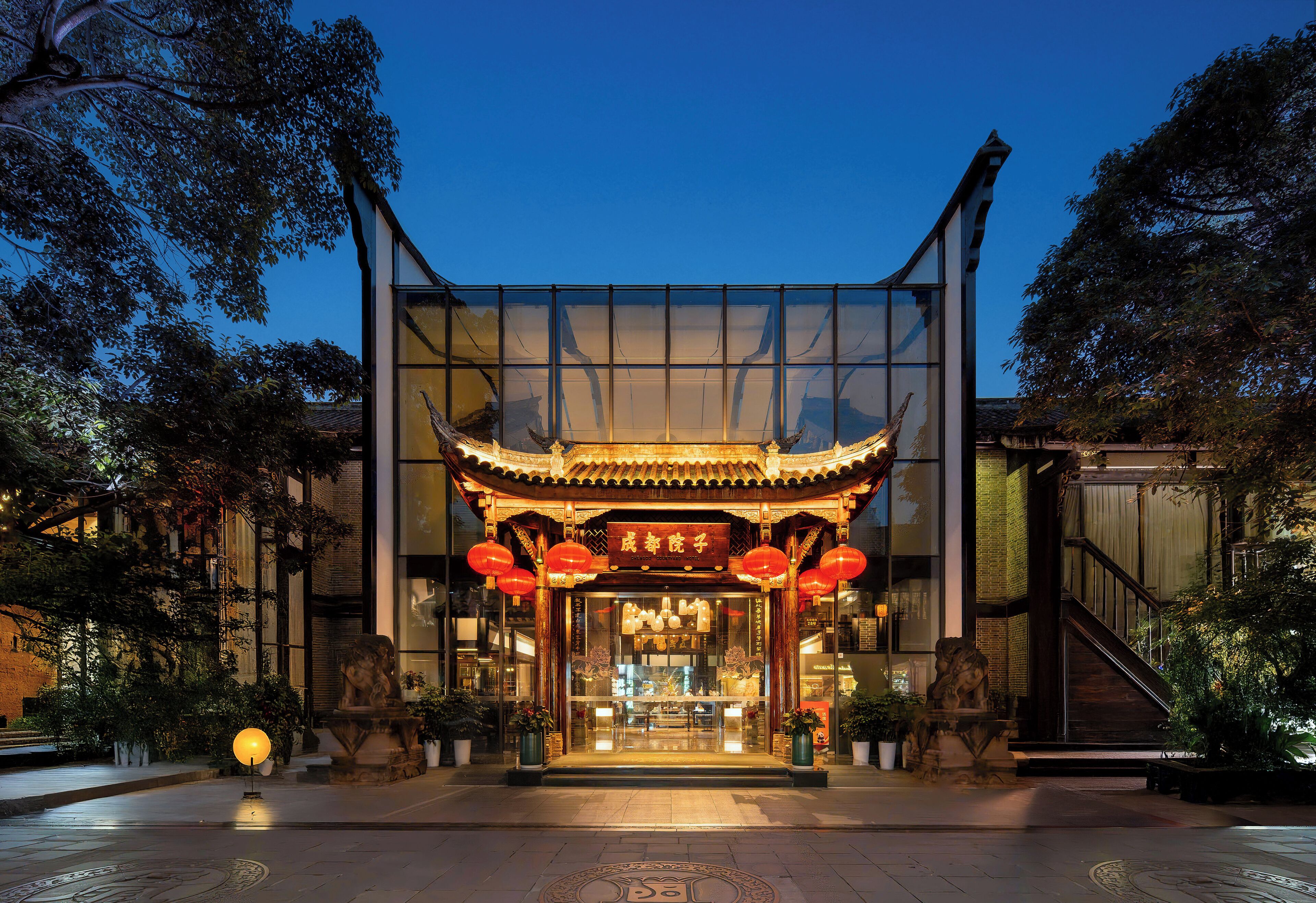 A traditional Chinese building with a modern glass facade, ornate wooden roof, and red lanterns.