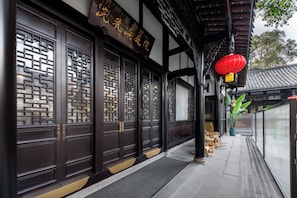 A traditional building with dark wooden doors, a sign with Chinese characters, and a red lantern. - CD YUEN CHI (Chengdu)