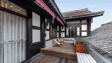 A traditional building with a wooden deck, a small seating area, and a potted plant.