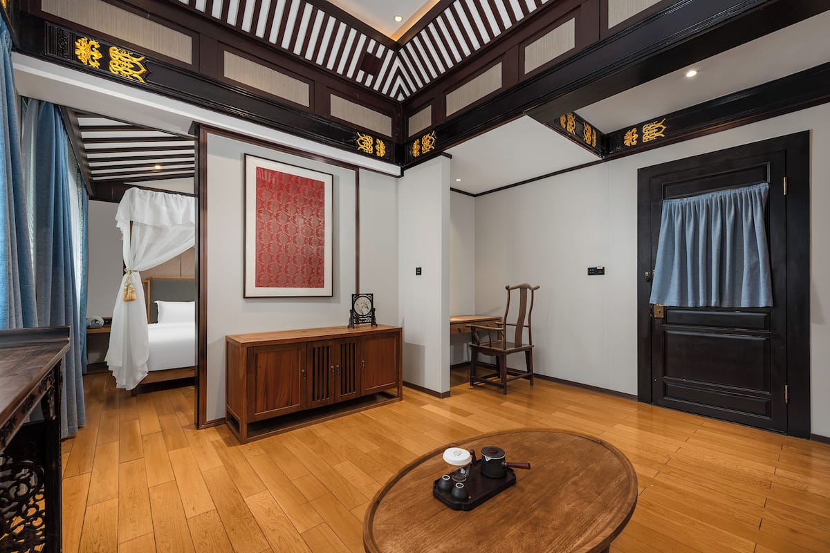 A traditional room with a bed, a wooden cabinet, a table with a tea set, and a door with a blue curtain.