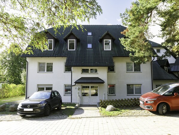 Two-story home with a symmetrical facade and central entrance, featuring a porch and a driveway with parking.