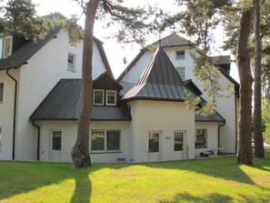Stylish two-story building with a central entrance and mature trees surrounding it.