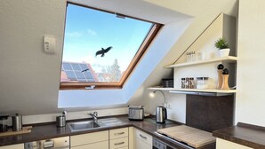 Una cocina moderna con tragaluz, horno empotrado y encimera con diversos electrodomésticos.