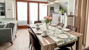 Un comedor con una mesa de madera dispuesta para cuatro personas, rodeada de sillas tapizadas.