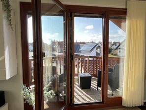 A room with a sliding glass door leading to an outdoor deck with a view of neighboring houses and a solar panel. - Haus an der Sonne by Interhome (Dittishausen)
