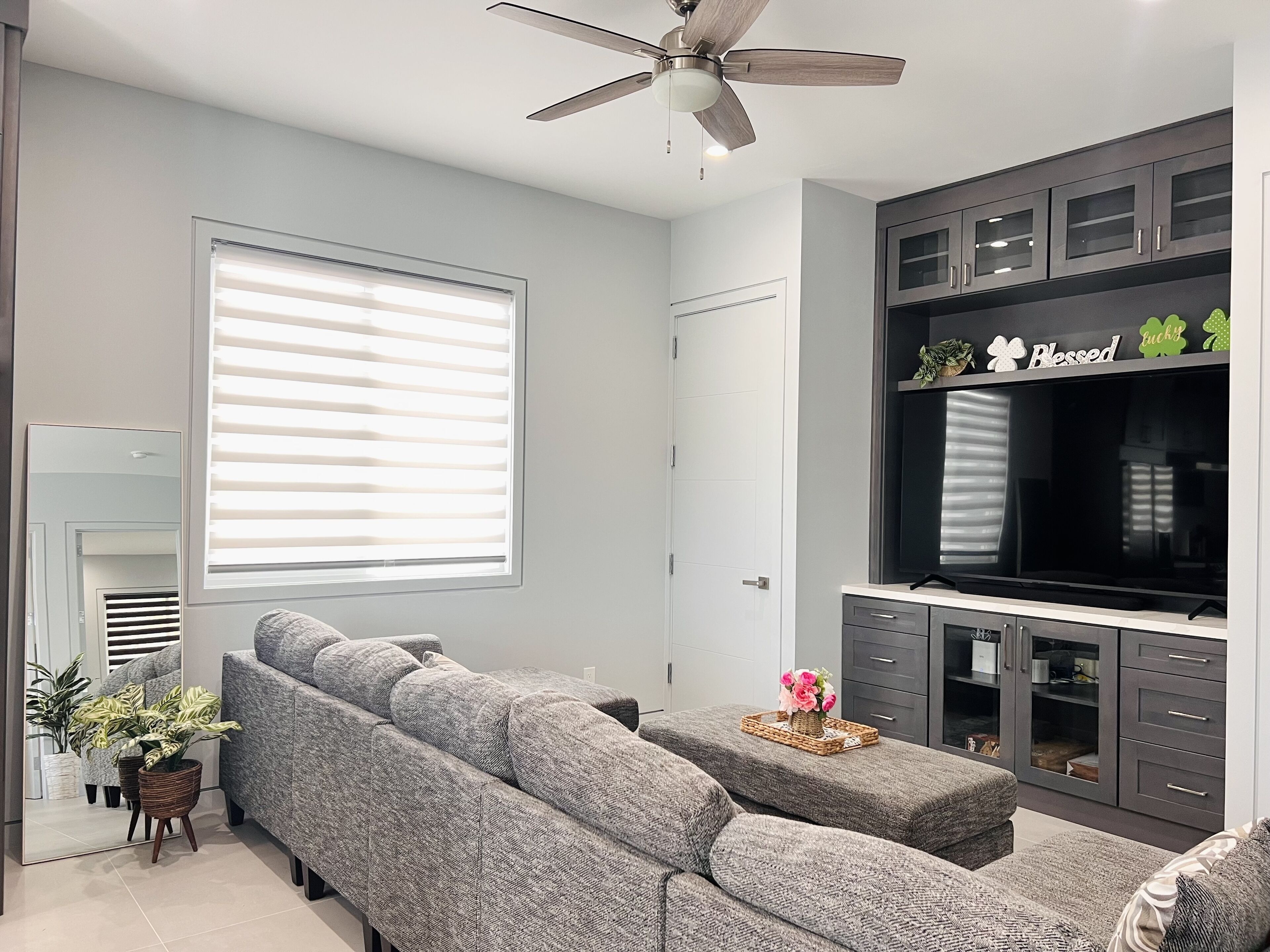 A modern living room with a sectional sofa, a flat-screen TV, and built-in cabinets.