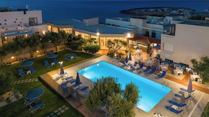 A modern hotel with a swimming pool, outdoor seating, and a view of the sea. - Creteco Hotel & Suites (Hersonissos)