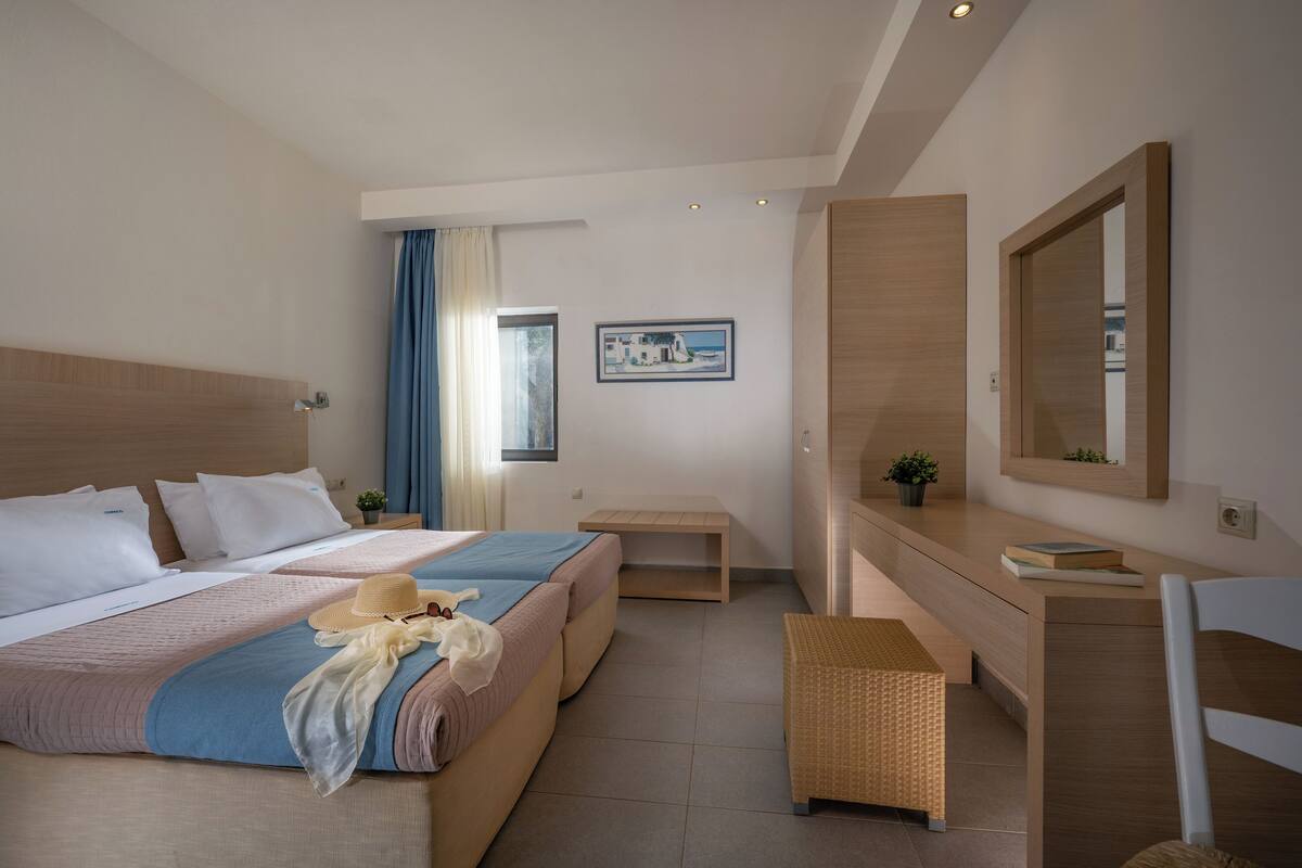 A modern hotel room with a large bed, a bedside table, a small desk, and a mirror.