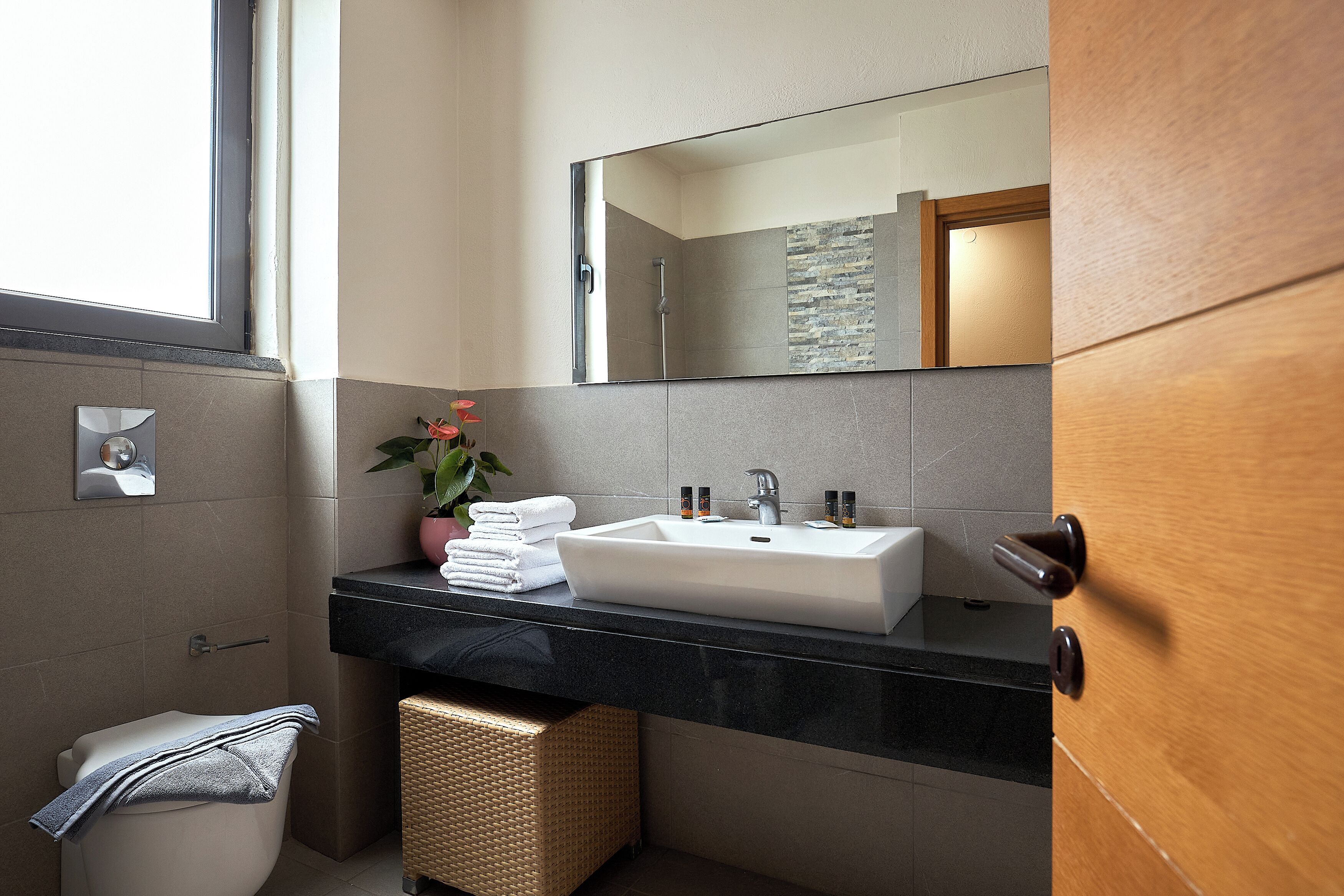 Un baño moderno con un espejo grande, un lavamanos y un inodoro.