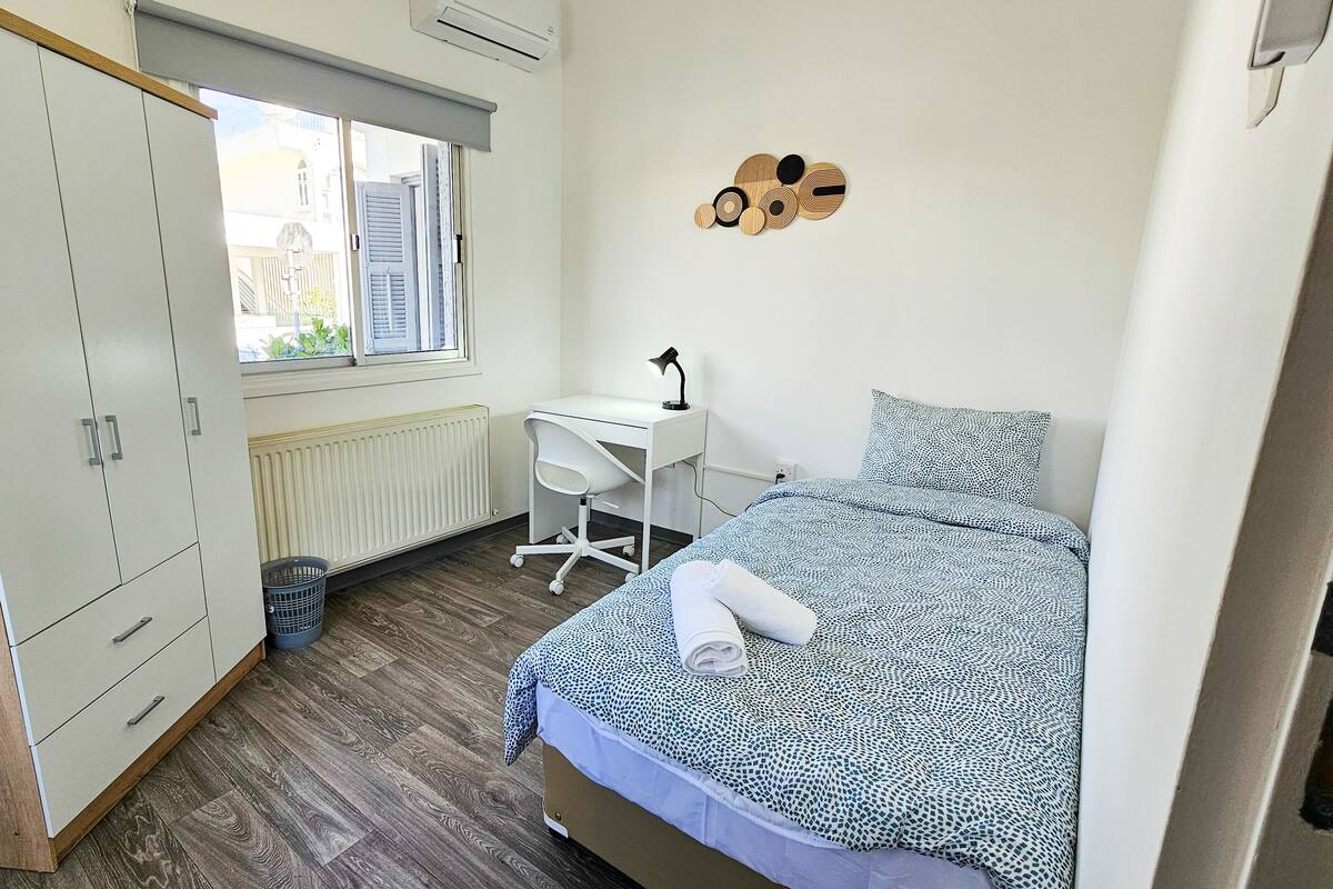 A bedroom with a bed, a desk, and a wardrobe.