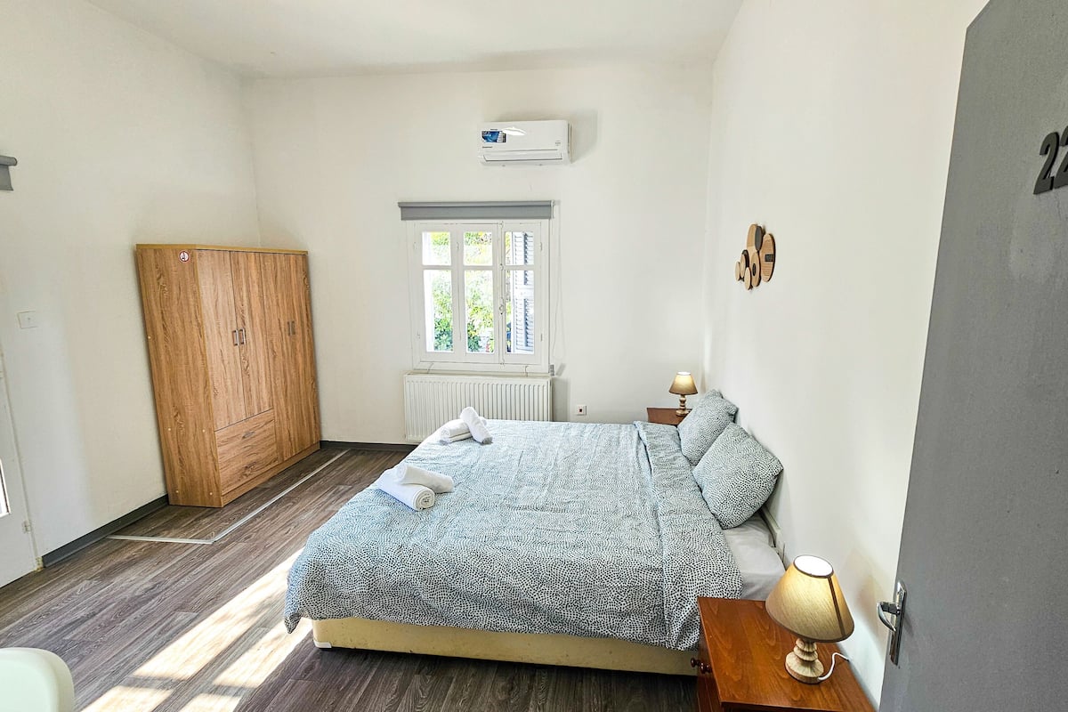 A bedroom with a bed, a wardrobe, a window, and a door with the number 22.