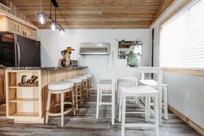 A kitchen with wooden cabinets, a refrigerator, a bar area with stools, and a dining table with chairs. - Sunset Beach View on Otter Tail Lake (Otter Tail)