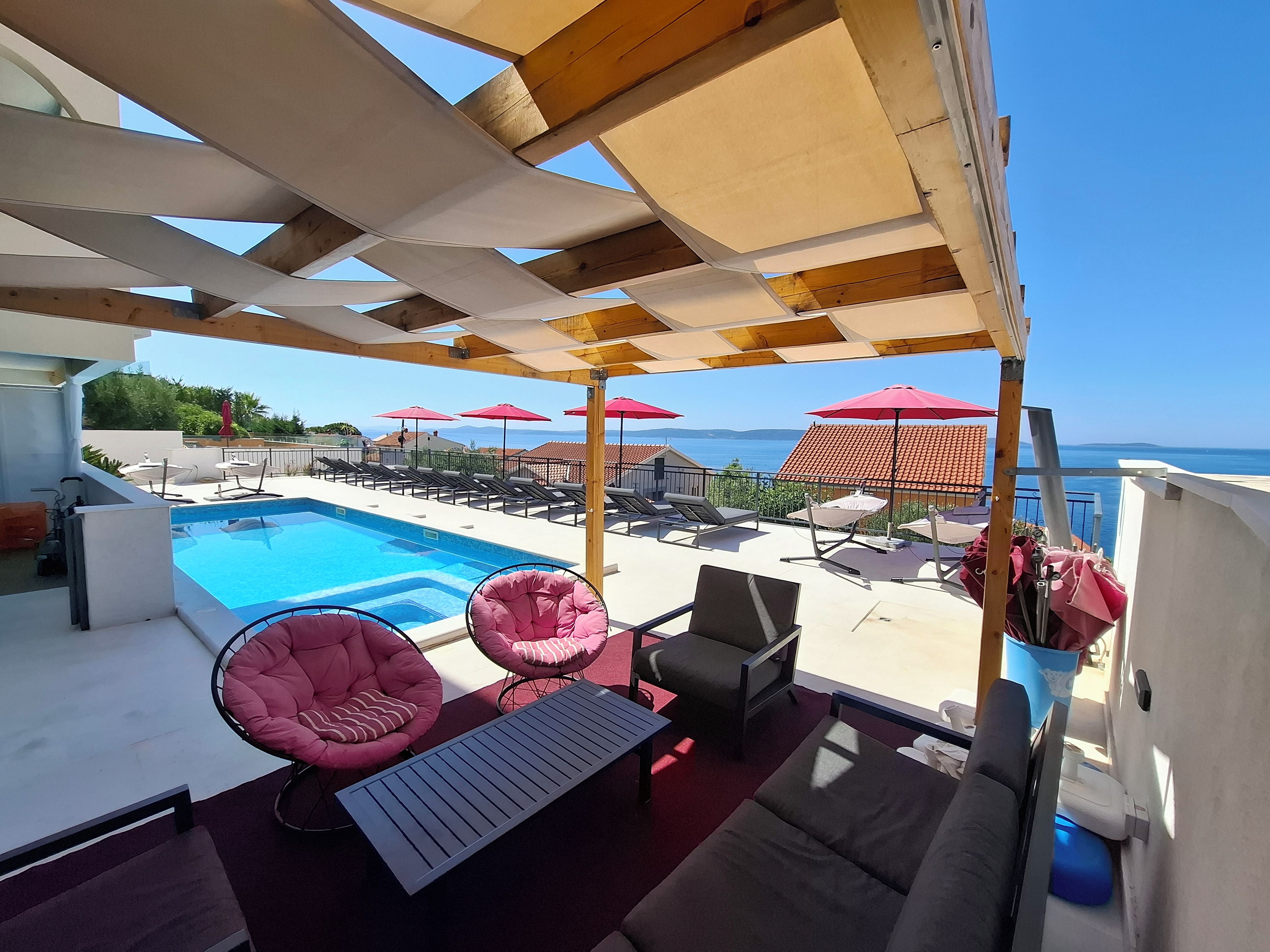 A poolside area with lounge chairs, umbrellas, and a view of the sea.