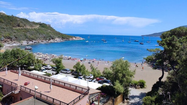 A beach with boats, umbrellas, and people. - Casa Diana, a few steps from Porto Azzurro center! (Porto Azzurro)