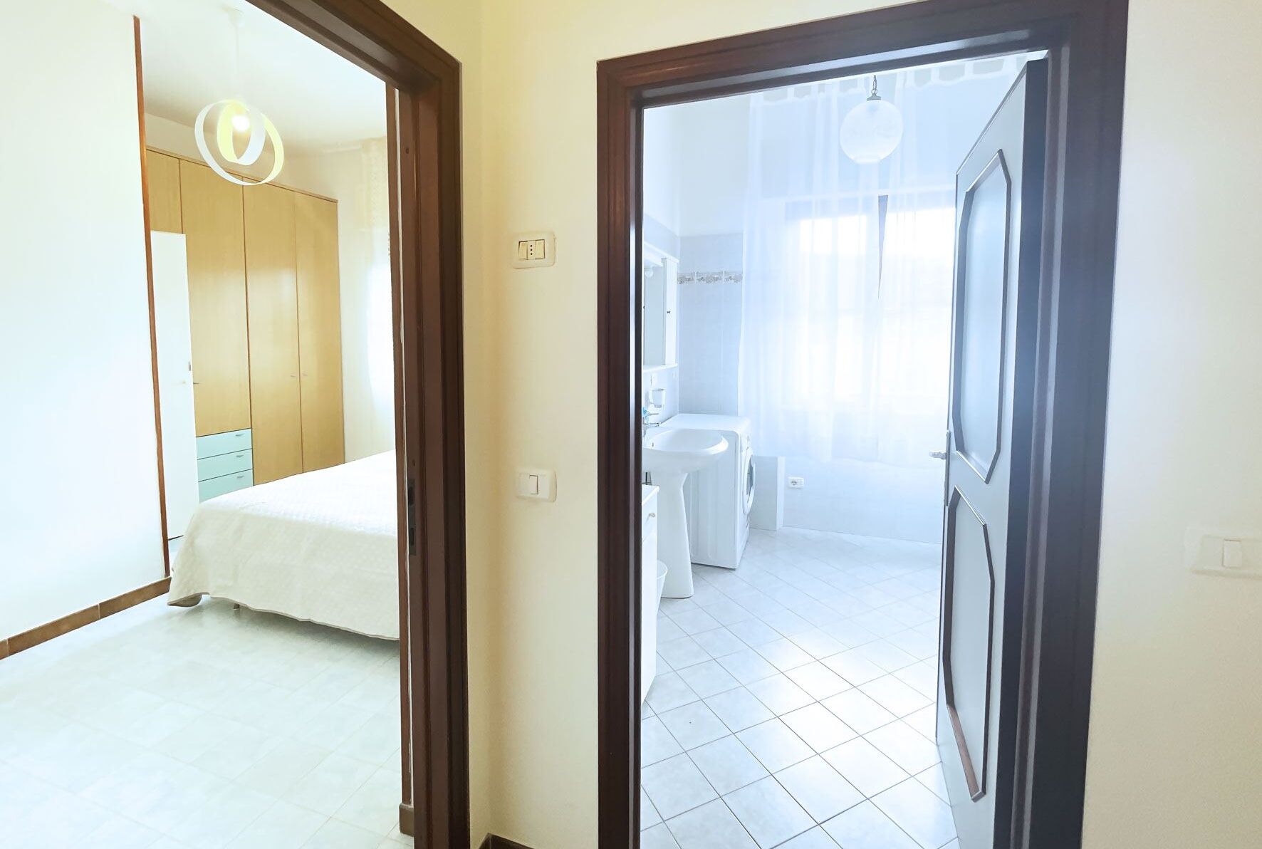 Una habitación de hotel con una cama, un armario, un baño con lavamanos y lavadora.