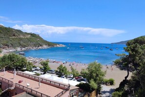 Una playa con barcos, sombrillas y coches.