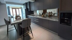 A modern kitchen with dark cabinetry, a central island, and bar stools.